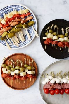 three plates with skewered meats and vegetables on them, one has cheese