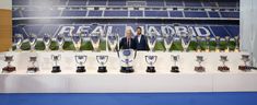 a man standing in front of trophies on display at a soccer stadium with the words real madrid written on it