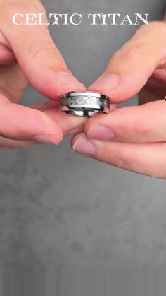 two hands holding a wedding ring with the words celtic titan written on it in front of them