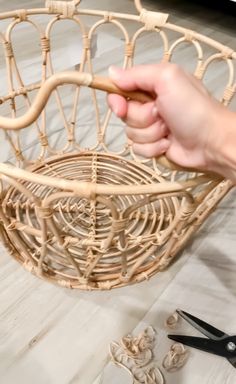 a person is holding scissors near a basket that has been made out of wicker