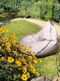 a large bean bag sitting on top of a lush green field next to yellow flowers