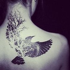 a woman's back with a bird and tree tattoo on it