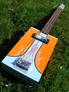 an orange and blue guitar laying in the grass