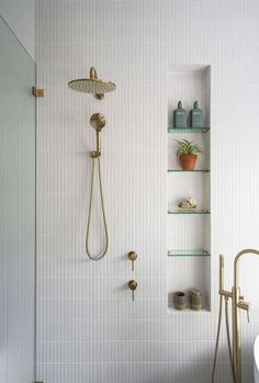 a bathroom with a shower, toilet and shelves on the wall next to each other