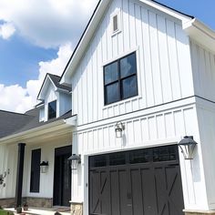 a white house with black garage doors and windows