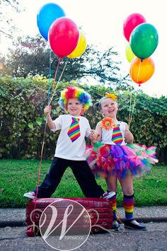 two children dressed in clown costumes holding balloons