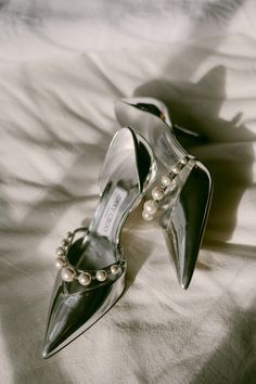 a pair of high heeled shoes with pearls on them