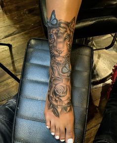 a woman's foot with a tiger tattoo on it and roses around the ankles