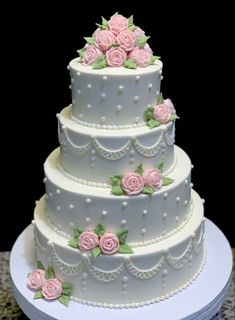 a three tiered wedding cake with pink roses on it's side and white icing