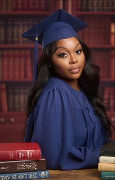 a woman wearing a graduation cap and gown sitting in front of books