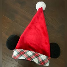 a mickey mouse hat on top of a wooden floor with a red and white checkered blanket