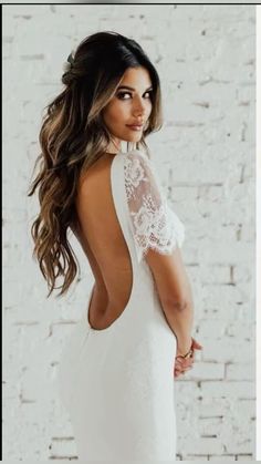 the back of a woman's white wedding dress with lace detailing and open shoulders