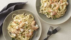 two plates of pasta with shrimp and basil