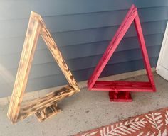 two wooden triangulars sitting next to each other on the ground in front of a house