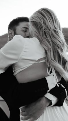 a man and woman embracing each other in front of a car