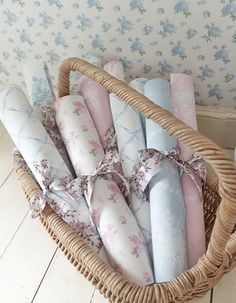 a wicker basket filled with blue and pink rolled up napkins next to a wallpapered wall