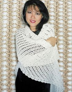 a woman standing in front of a wall wearing a white shawl and black pants