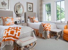 two beds with orange and white bedding in a bedroom