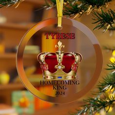 a glass ornament with a crown on it hanging from a christmas tree branch