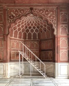 an ornate doorway with stairs leading up to the second floor in a building that is painted red and white