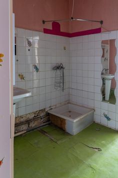 an old bathroom with green flooring and pink walls