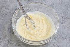 a glass bowl filled with cream and two whisks sticking out of the top