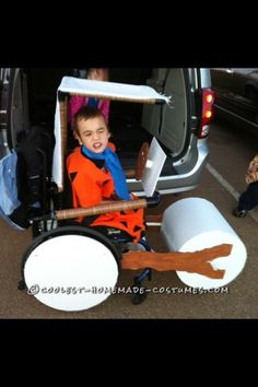 a young boy sitting in a wagon filled with items