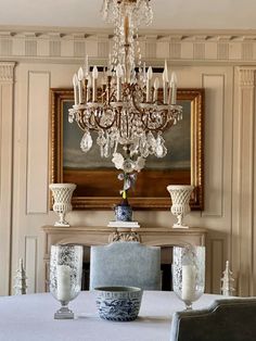 a chandelier hangs above a dining room table with blue and white dishes on it