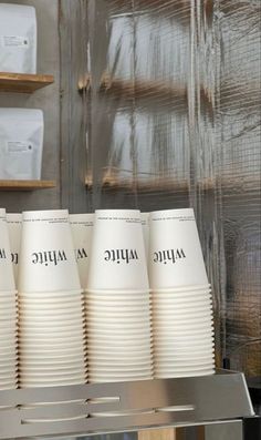 four white cups sitting on top of a metal shelf