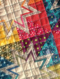 a close up view of a quilt with many different colors and designs on it,