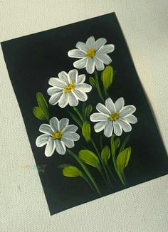 some white flowers are on a black and white background with green leaves in the center