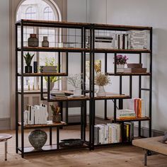 a living room filled with furniture and bookshelves next to a window on the wall