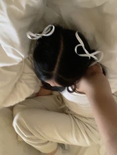 a woman laying on top of a bed under a white comforter covered in pillows