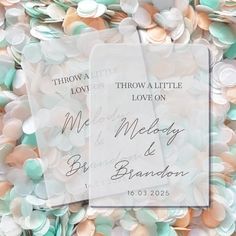 two wedding tags sitting on top of a pile of confetti