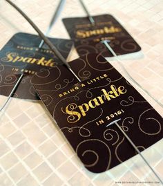 three black and gold sparkle tags sitting on top of a tiled floor