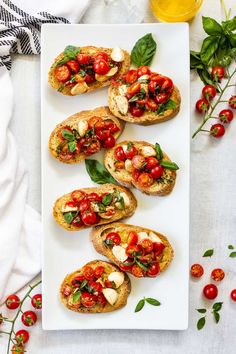 several pieces of bread with tomatoes and basil on top