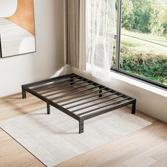 a metal bed frame sitting on top of a hard wood floor next to a window