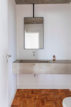 a bathroom with a mirror, sink and toilet in the corner next to a wooden floor