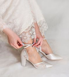 a woman tying her wedding shoes with lace on the bottom and heels in the middle