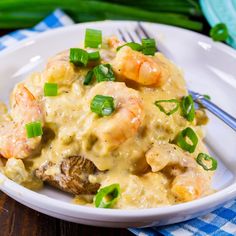 a white plate topped with shrimp and grits covered in gravy next to a fork