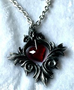 "An 1 ½\" long antiqued pewter pendant of a baroque scroll frame surmounted by a small skull and with a red Austrian crystal heart suspended at its centre. The pendant comes with a velvet gift pouch. Made by Kiss of a red rose with help from Alchemy England 1977." Kiss Decorations, Gilmore Style, Goth Vampire, Goth Accessories, Small Skull, Pewter Pendant, Love Pendant, Gothic Clothing, Sparkly Things