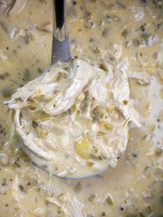 a ladle full of soup with chicken and broccoli in it is being stirred by a spoon