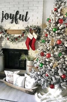 two christmas trees in front of a fireplace decorated with stockings and stocking hanging from the mantel