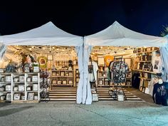 an outdoor market with white tents and pictures on the wall, in front of it