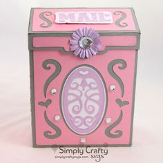 a pink and gray box with an ornate design on the lid, decorated with a flower