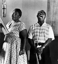 two people standing next to each other in front of a microphone and an old record player