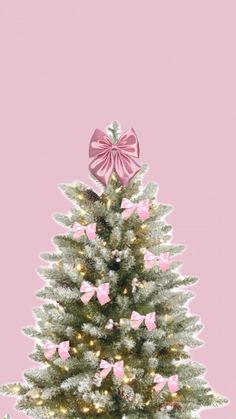 a white christmas tree with pink bows and lights on it's top, against a pink background