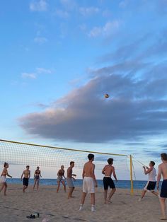 a group of young men playing volleyball on the beach at sunset or sunrise with one ball in the air