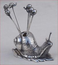 a silver snail figurine with three forks sticking out of it's back