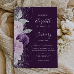 a purple and silver wedding card with roses on it, next to some white flowers